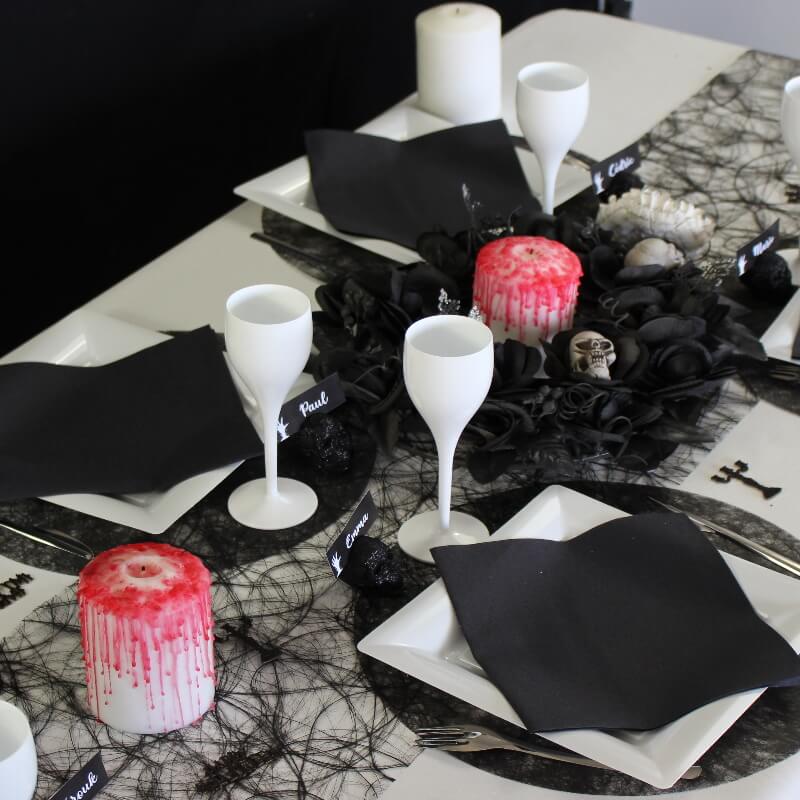 Décoration de table pour Halloween noire et blanche avec bougie ensanglantée.